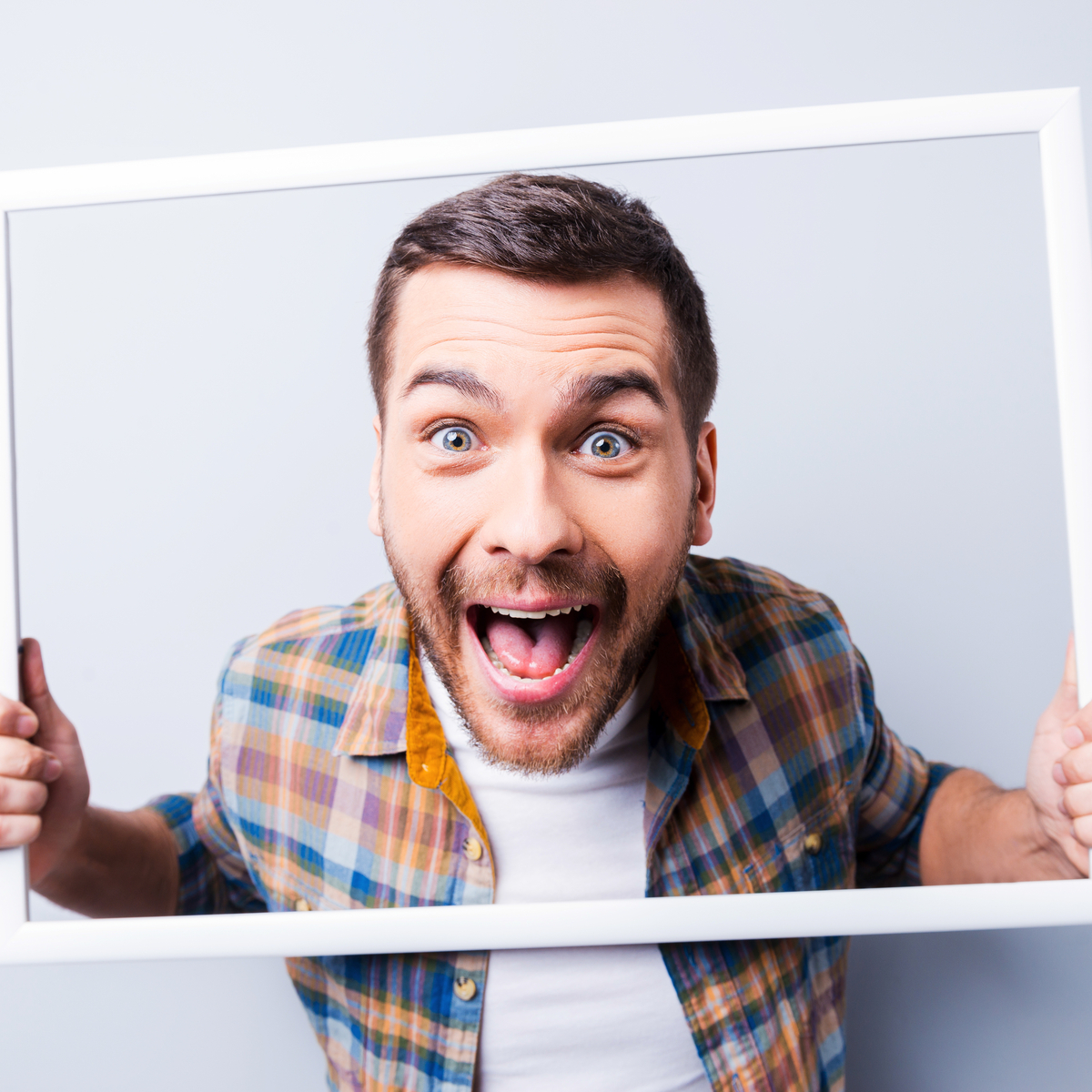 Smiling man holding picture frame around face