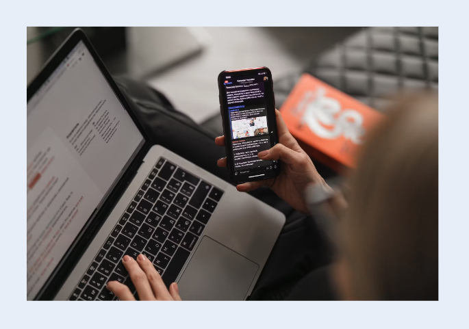 Image slide on Mentimeter. The image is centered in the slide, and is of someone using their phone and laptop to work.